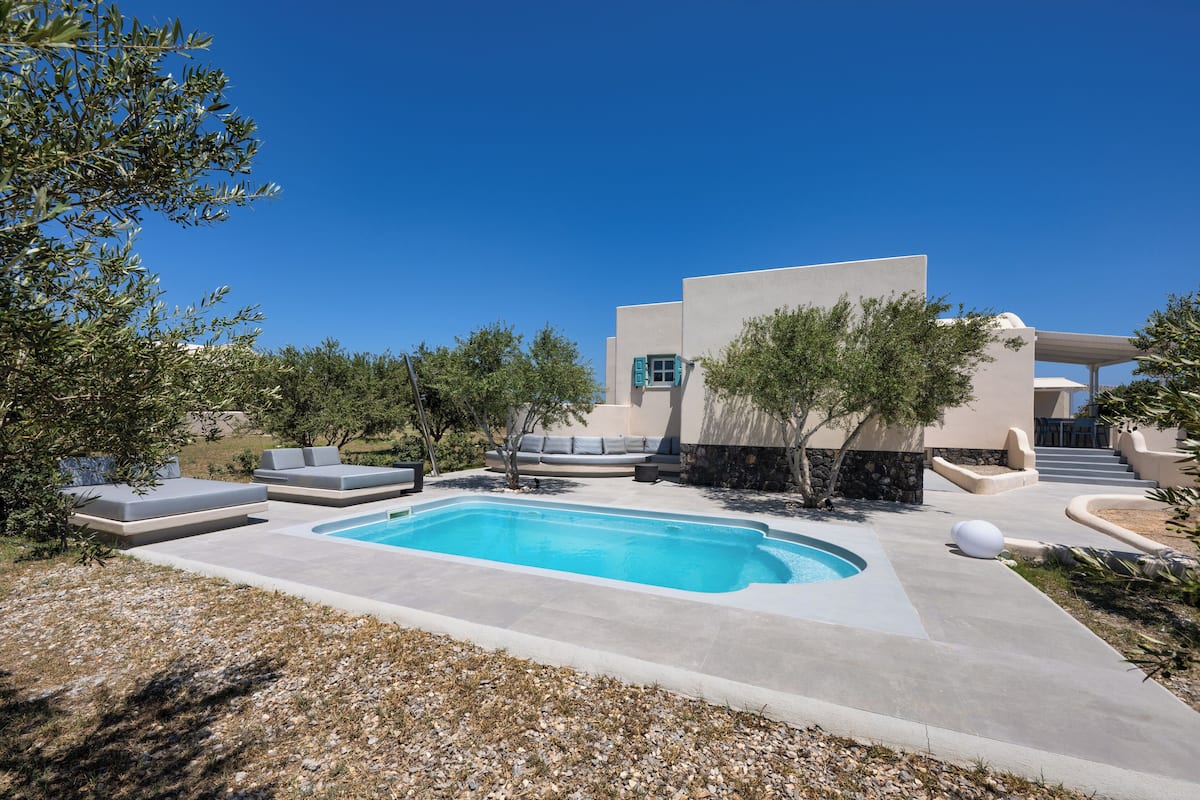 A modern outdoor pool area with a built-in seating area and a clear blue sky.