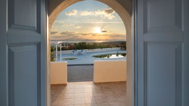 An open doorway leading to a terrace with a view of the sunset over a landscape. - Sienna Eco Resort (Santorini)