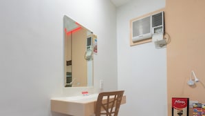 Ein Badezimmer mit Waschbecken, Spiegel, Stuhl, Klimaanlage und Wandleuchte.
