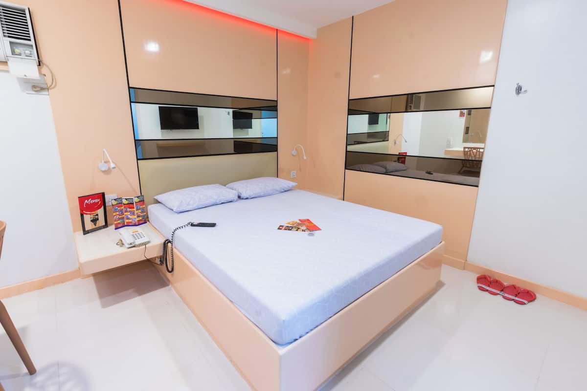 A bedroom with a bed, bedside table, and a mirror.