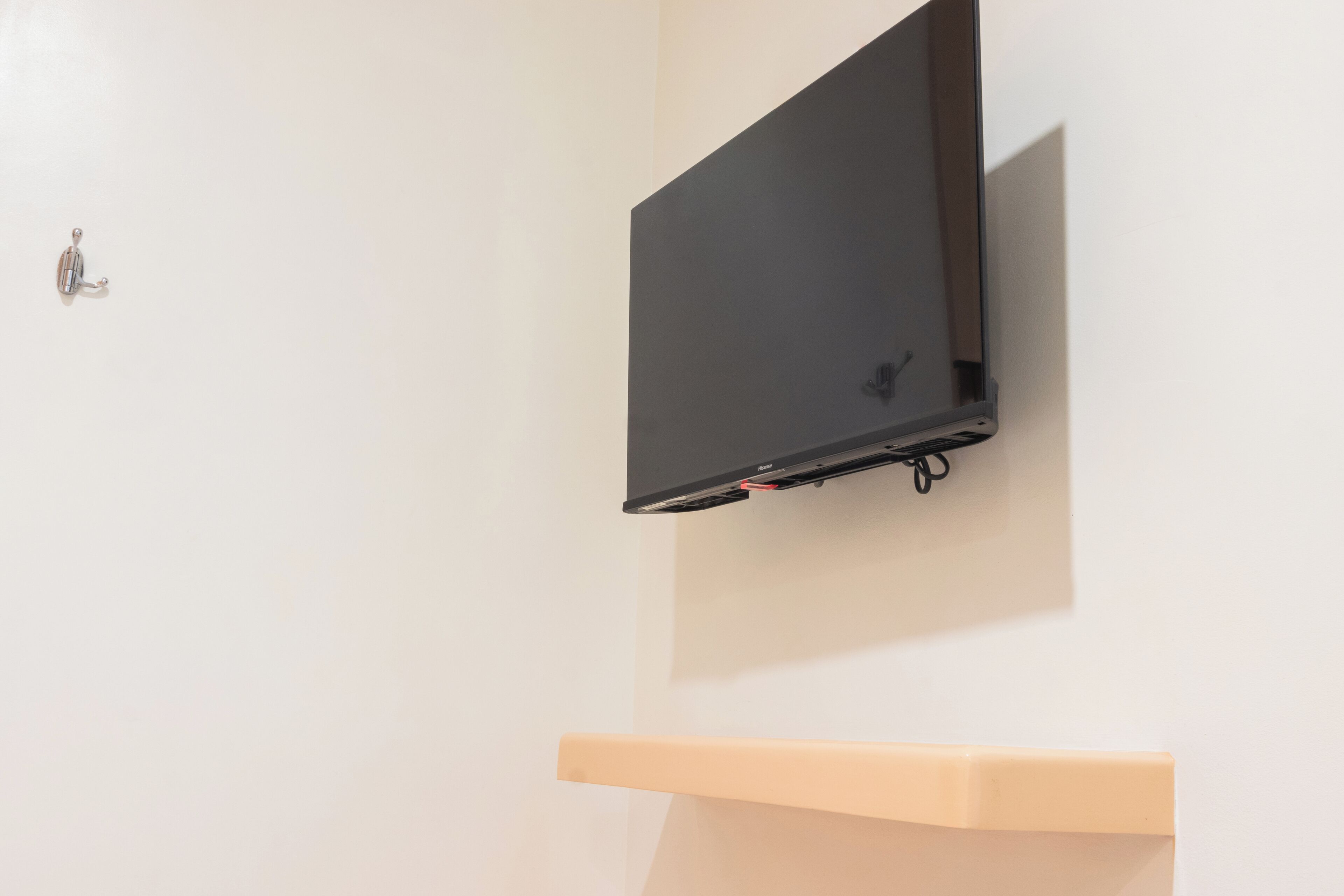 Een flatscreen televisie bevestigd aan een witte muur, met een houten plank eronder.