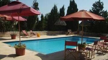 Una piscina al aire libre, sombrillas, tumbonas