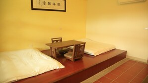 Quarto com cama, uma mesinha e uma cadeira. Há um quadro na parede e um ar condicionado fixado na parede.