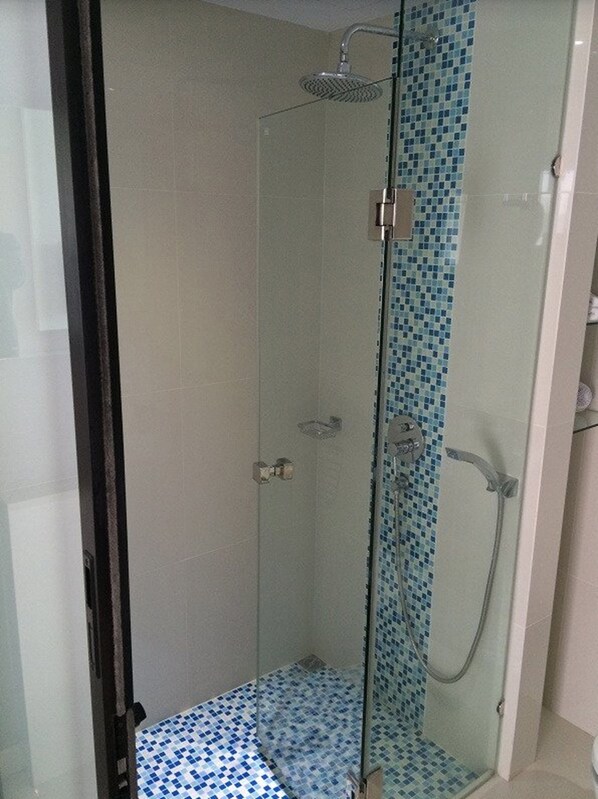 A glass-enclosed shower with a tiled floor and a showerhead. - Serenotel Pattaya Beach Front (Pattaya)