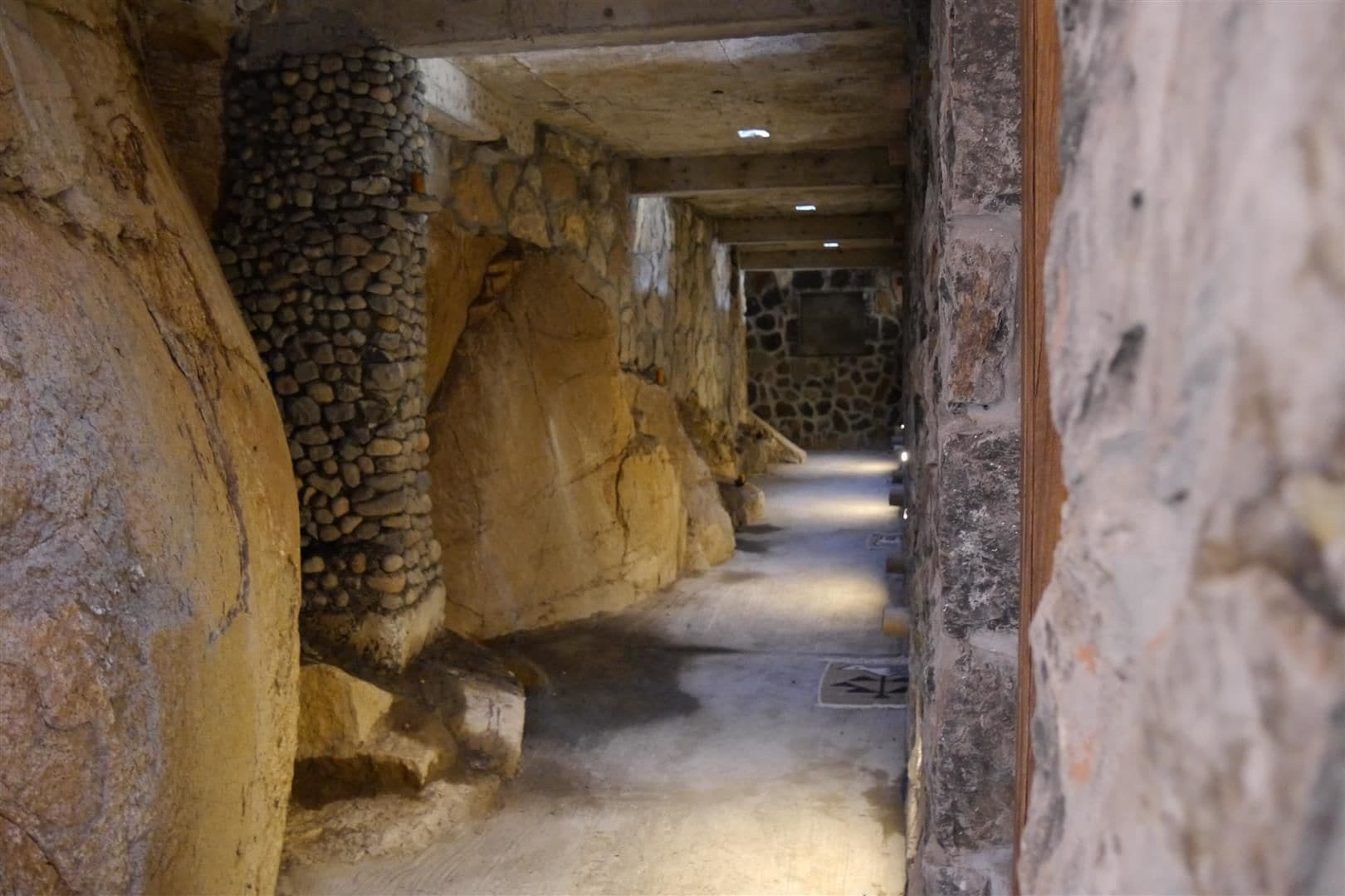 A narrow corridor with stone walls and a wooden ceiling.