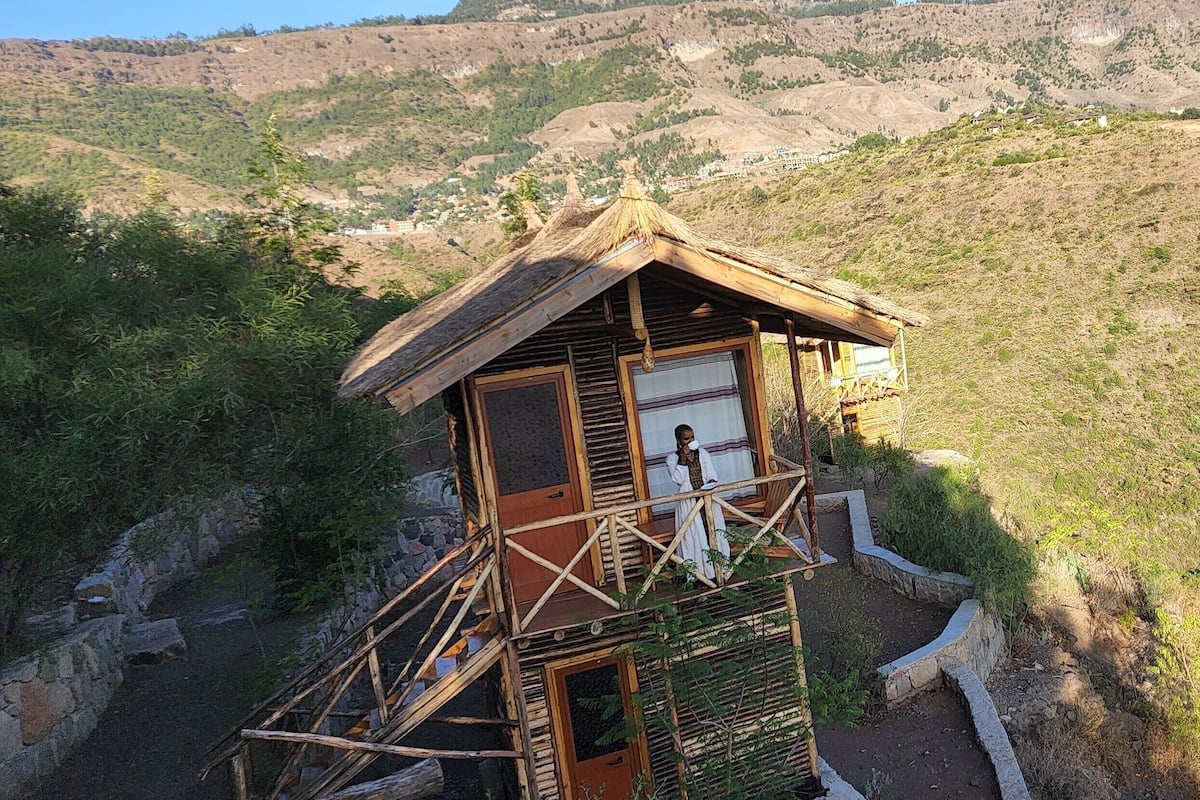 Un chalet rustique en bois, doté d’un balcon, niché au cœur d’un paysage montagneux.