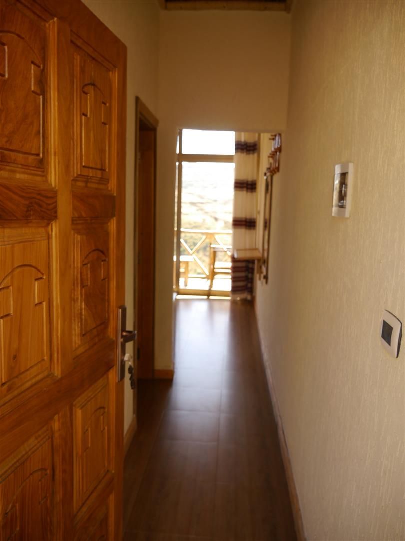 Un pasillo con puertas de madera, un interruptor de luz y una ventana con persianas.