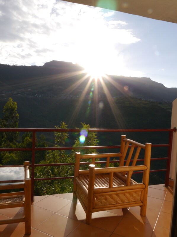 A balcony with a wooden chair and a view of a mountainous landscape.