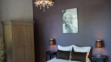 Un dormitorio con cama, lámparas de noche, un armario de madera y un candelabro.
