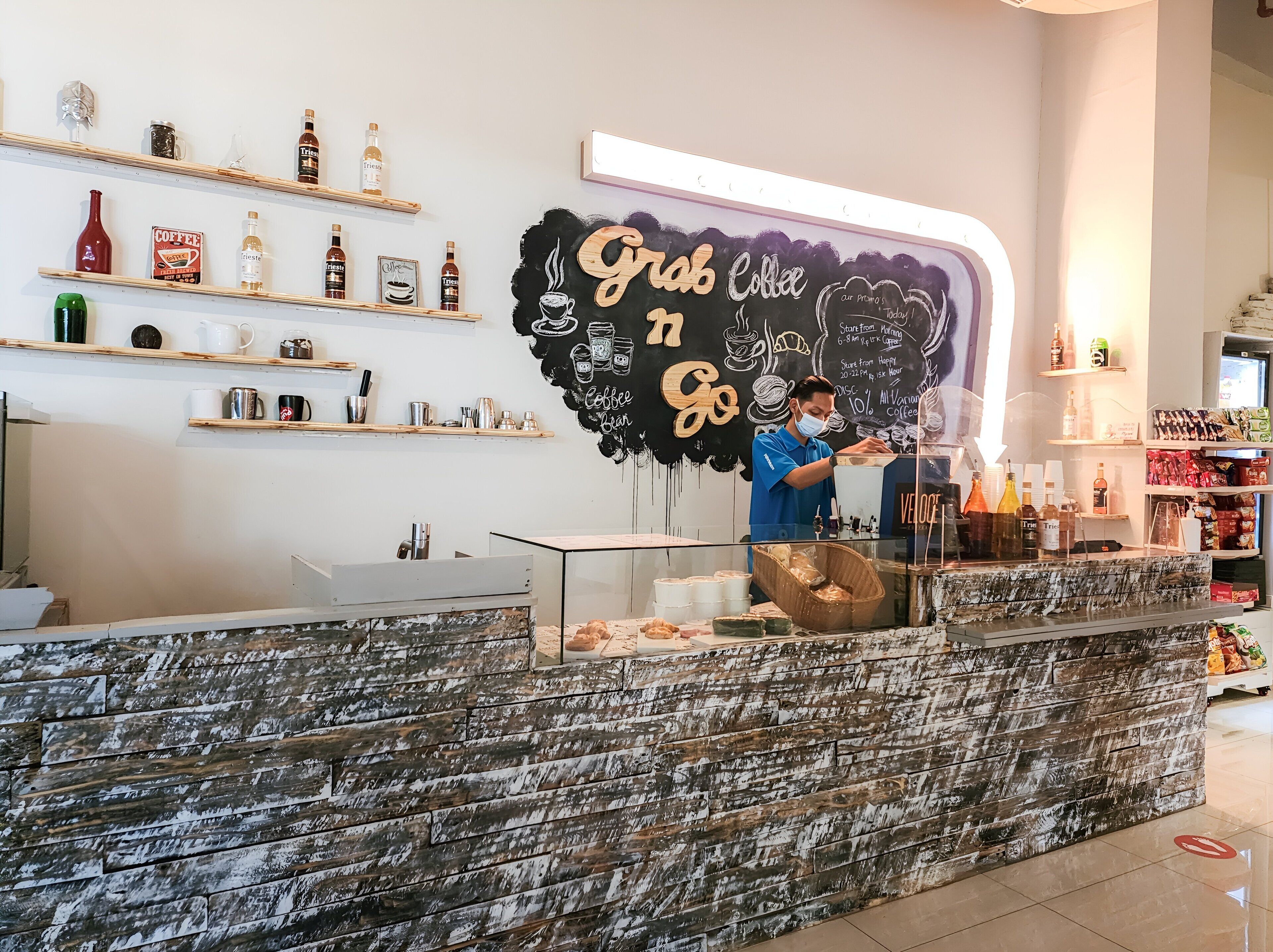 A coffee shop interior with a chalkboard wall displaying 'Grab Coffee Go' and various coffee products on shelves.