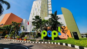 Un hotel moderno con un llamativo letrero que dice 'pop!', un edificio de varios pisos y un área de estacionamiento.
