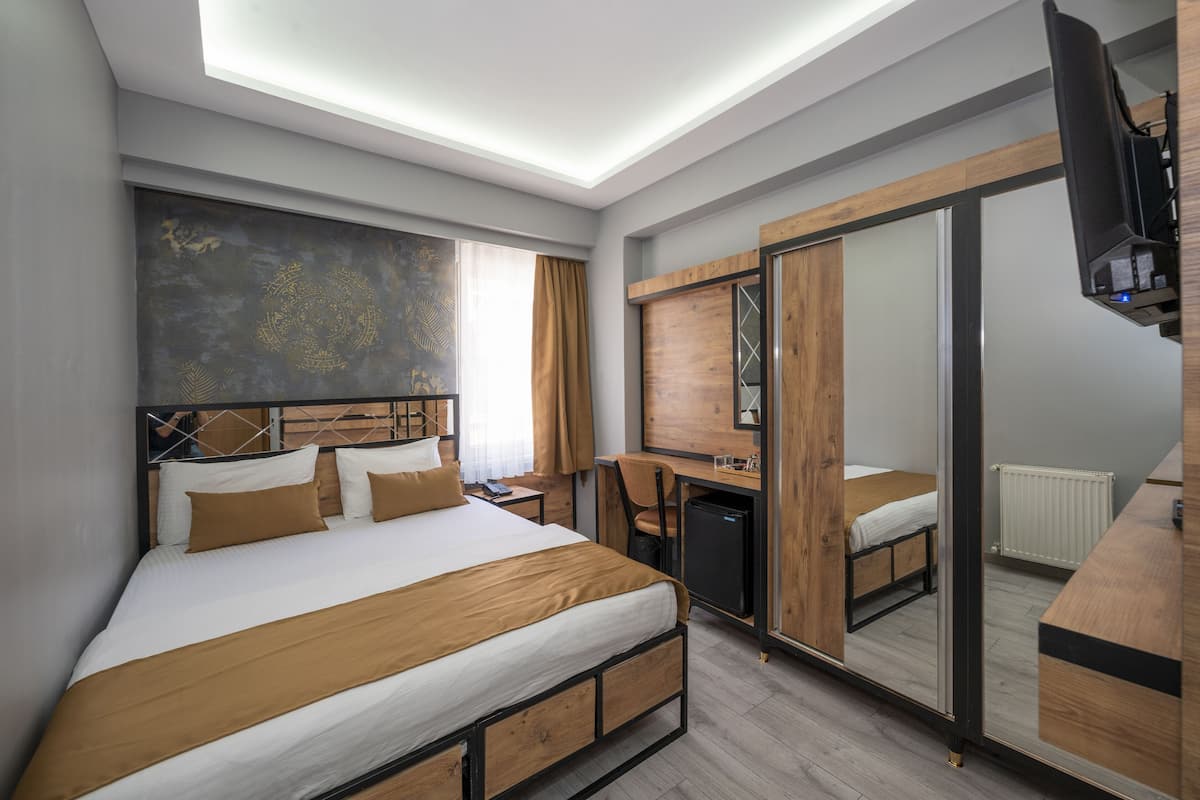 Une chambre d’hôtel moderne équipée d’un grand lit, d’un bureau, d’une chaise, d’un miroir et d’une télévision.