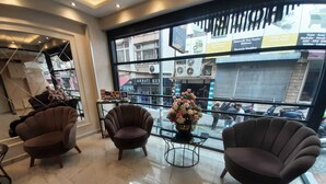Una hall d'hotel con arredi moderni, un tavolo in vetro con un vaso di fiori e vista sulla strada.