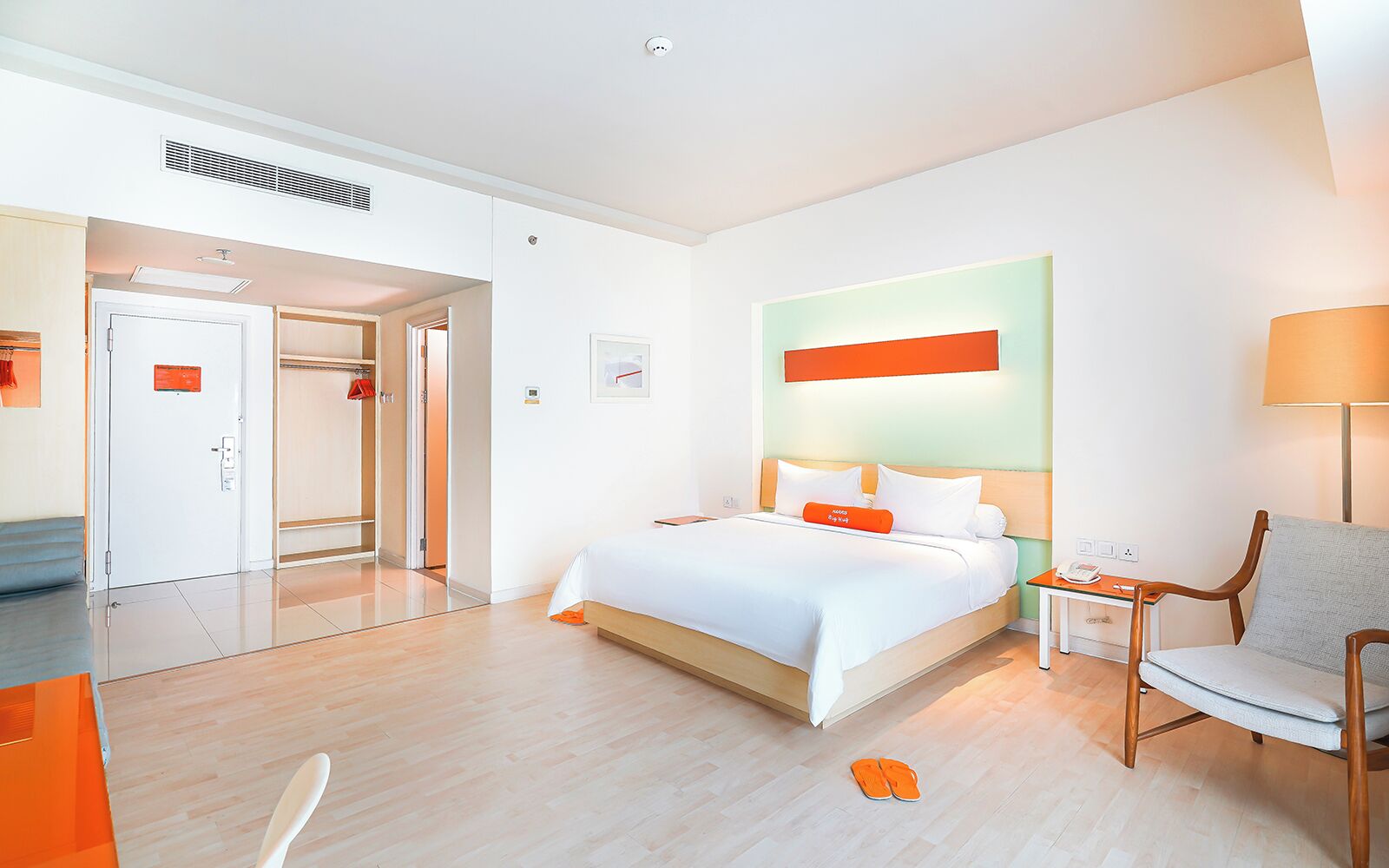 A hotel room with a bed, a desk, a chair, and a bathroom with a shower and toilet.