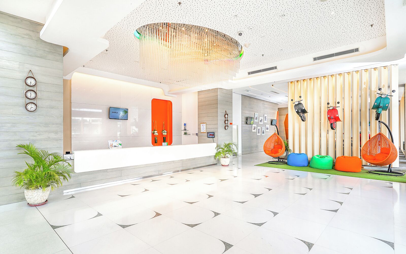A modern lobby with a reception desk, a large chandelier, and colorful seating areas.