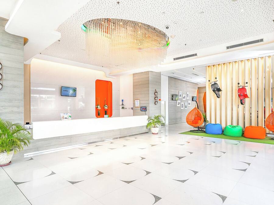 A modern lobby with a reception desk, a large chandelier, and colorful seating areas.