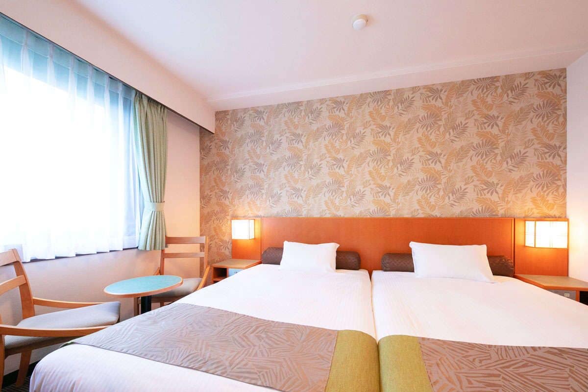 Een hotelkamer met een groot bed, twee nachtkastjes, een klein rond tafeltje en een stoel.