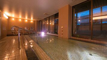 A swimming pool area with tiled flooring, a metal handrail, and a large window with a view of the outside.