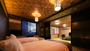 Une chambre d’hôtel avec deux lits, une grande fenêtre avec stores, un intérieur de style japonais traditionnel et une vue sur un jardin.