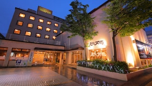 Un hôtel avec des fenêtres illuminées, une entrée bien visible et une enseigne avec des caractères japonais.