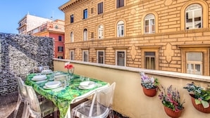 A rooftop terrace with a table set for dining, clear chairs, and potted plants. - M&L Apartment - case vacanze a Roma (Rome)