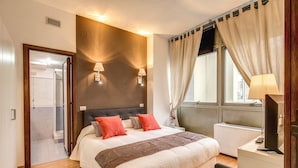 A hotel room with a bed, bedside lamps, a desk with a computer, and a window with curtains. - M&L Apartment - case vacanze a Roma (Rome)