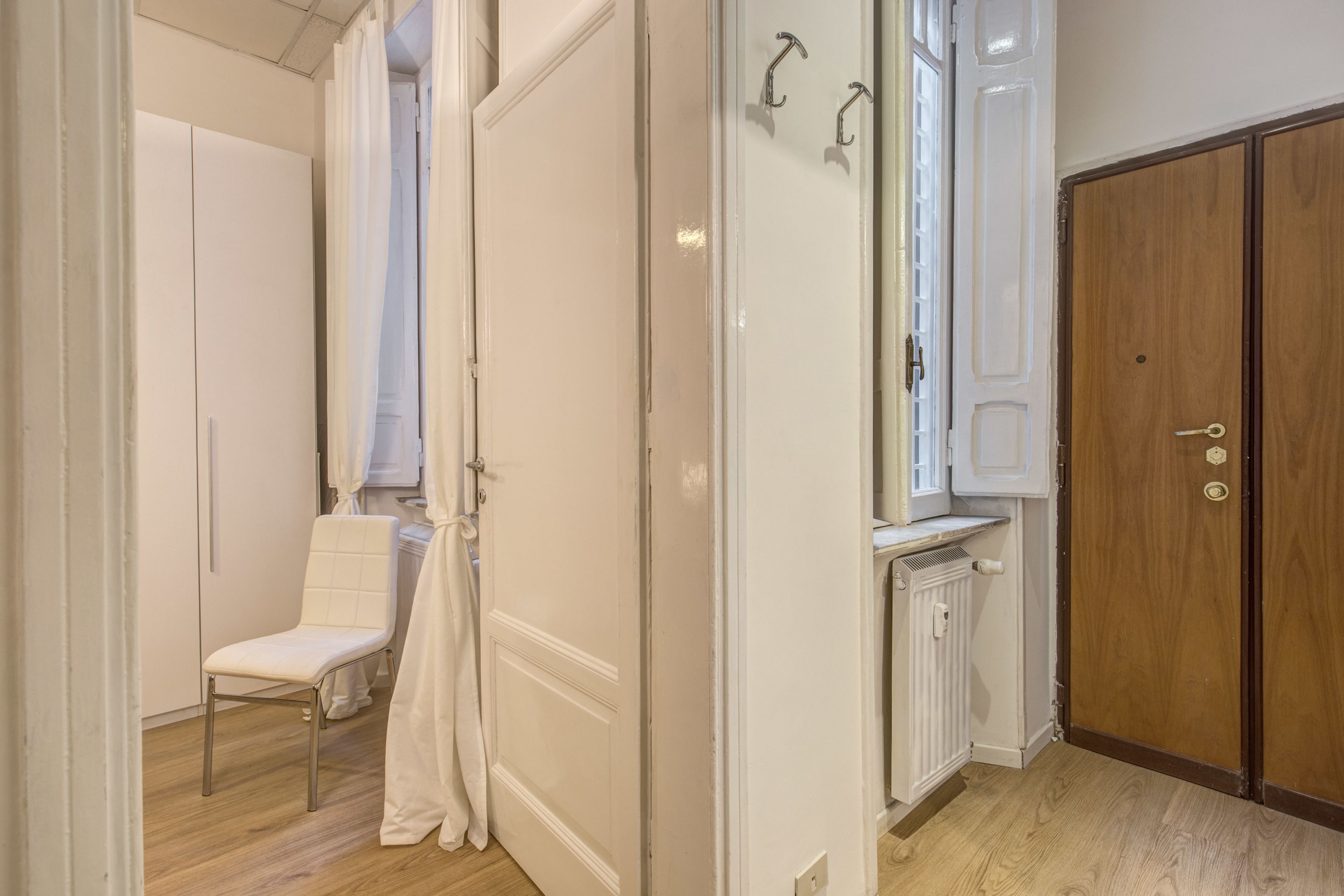 Ein Zimmer mit einem weißen Wandschrank, einem weißen Stuhl und einer Heizung.