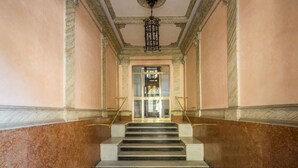 A grand staircase with marble walls and a patterned floor leading to a glass door. - M&L Apartment - case vacanze a Roma (Rome)