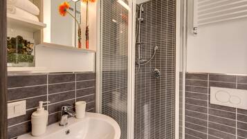 Een badkamer met een wastafel, spiegel, douche en handdoekhouder.