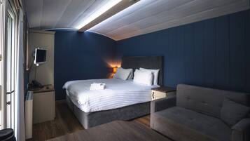 A bedroom with a bed, bedside table, lamp, and a sofa.