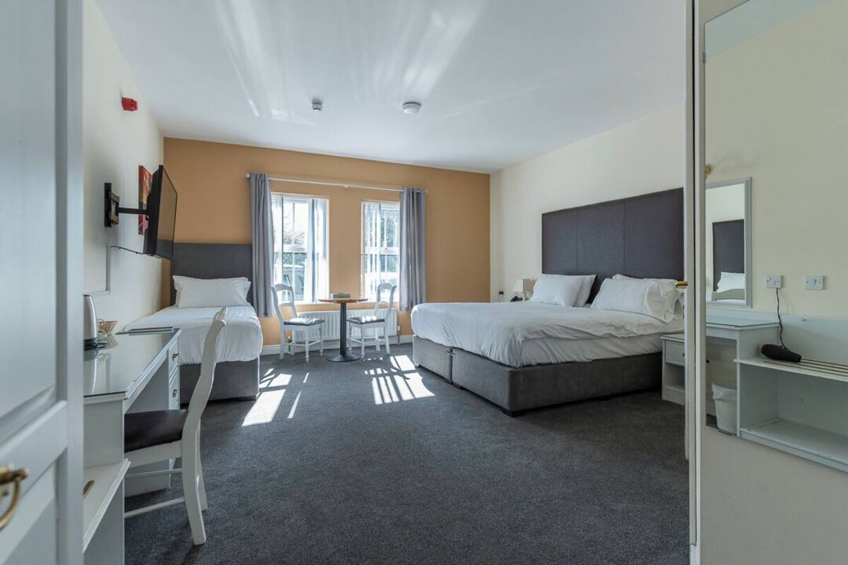 A hotel room with a bed, a desk, a chair, and a window.