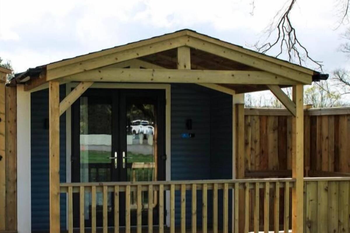 A wooden structure with a porch and a door, surrounded by a fence.