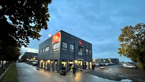 Ein modernes Hotel mit Empfangsbereich, Parkplatz und umgebenden Bäumen.