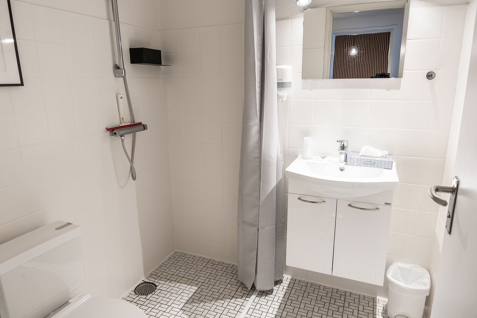 A modern bathroom with a shower, a sink, and a toilet.