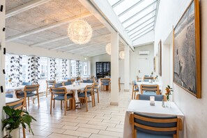 Une salle à manger spacieuse avec de hauts plafonds, de grandes fenêtres et des lustres modernes.