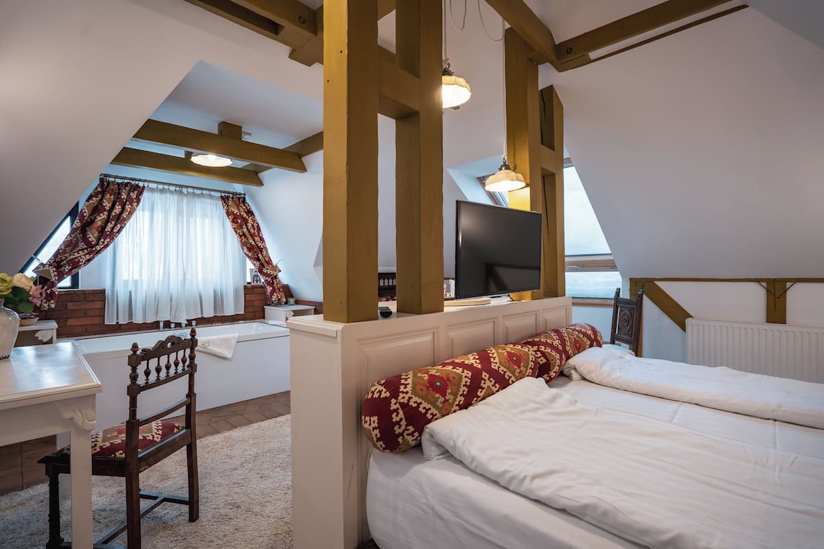 Quarto com uma cama, uma escrivaninha e uma televisão.