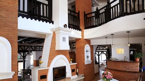 Un vestíbulo espacioso con chimenea, una recepción y un balcón con barandilla negra.