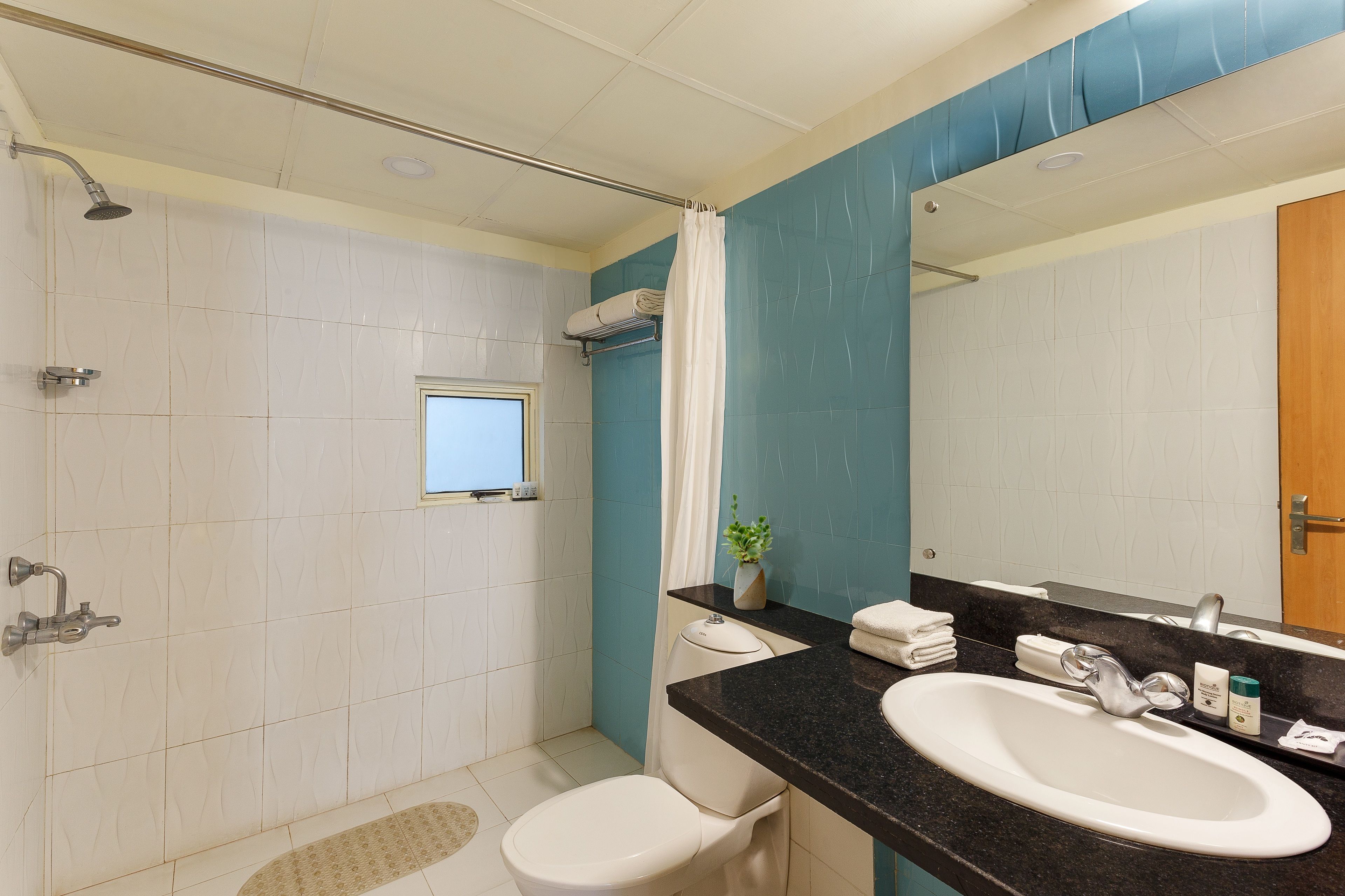 Un baño con ducha, inodoro, lavamanos y ventana.