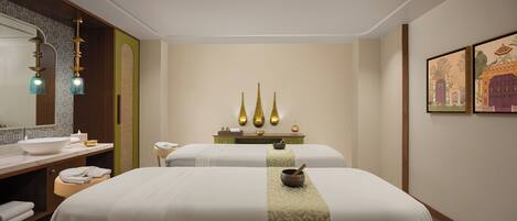 Una habitación de hotel con una cama grande, un baño con lavamanos y espejo, y una mesita con objetos decorativos.