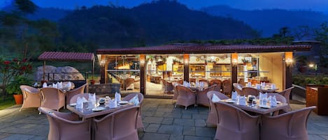 An outdoor dining area with wicker furniture and a view of a restaurant with a red-tiled roof.