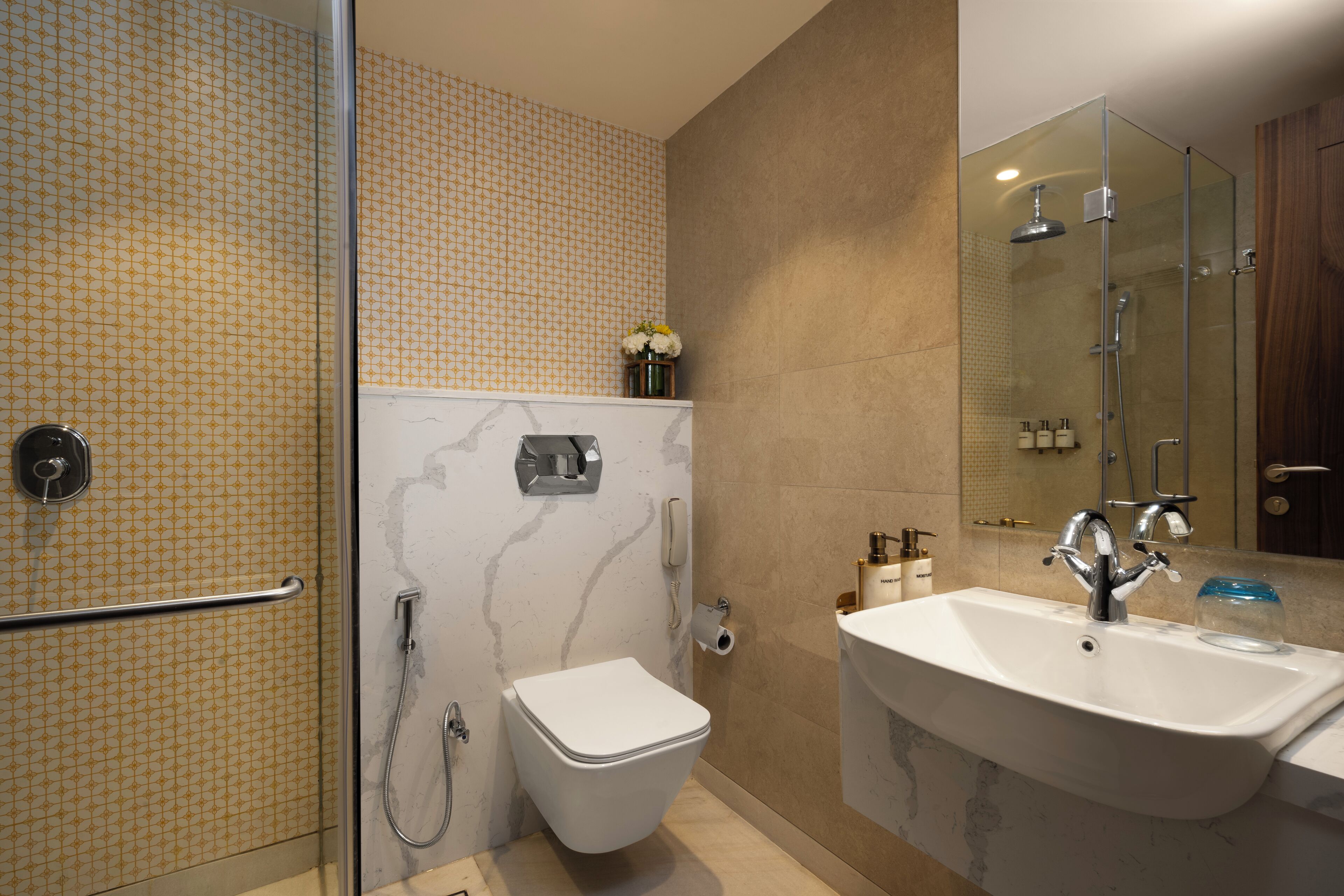 Un baño moderno con cabina de ducha de vidrio, inodoro blanco, lavamanos de mármol y un espejo.