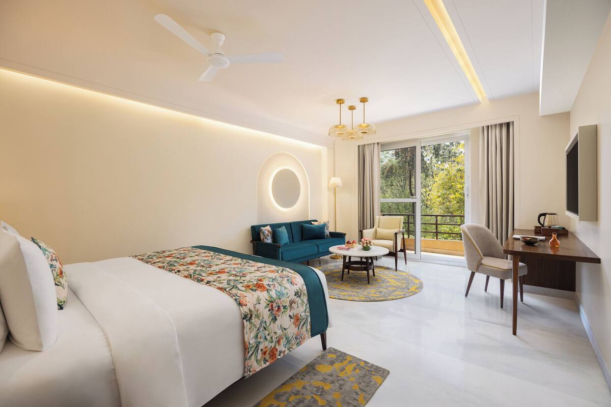 Quarto de hotel moderno com uma cama grande, um sofá, uma escrivaninha e um espaço de jantar.