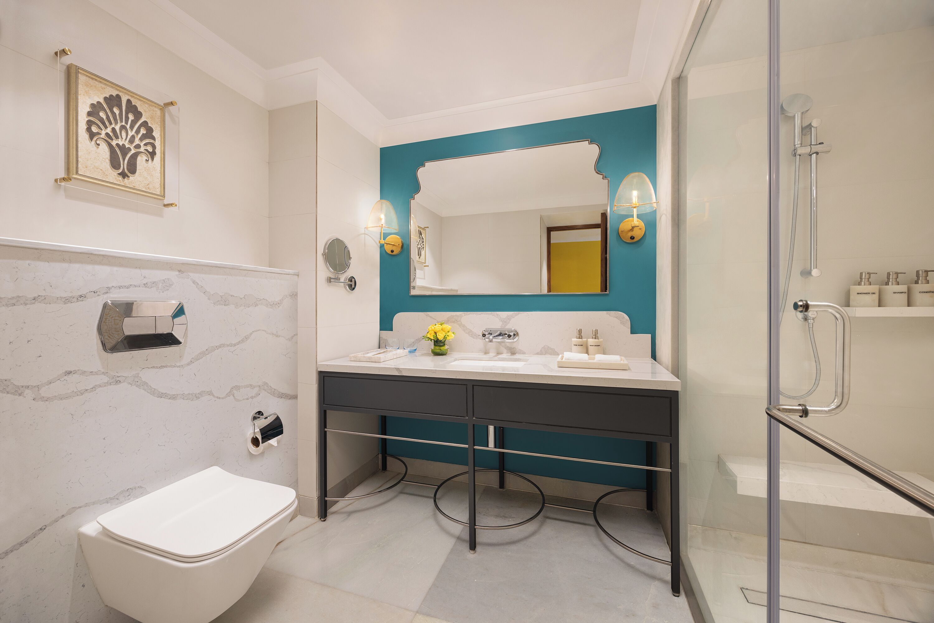 A modern bathroom with a white toilet, a sink with a vase of flowers, and a large mirror.