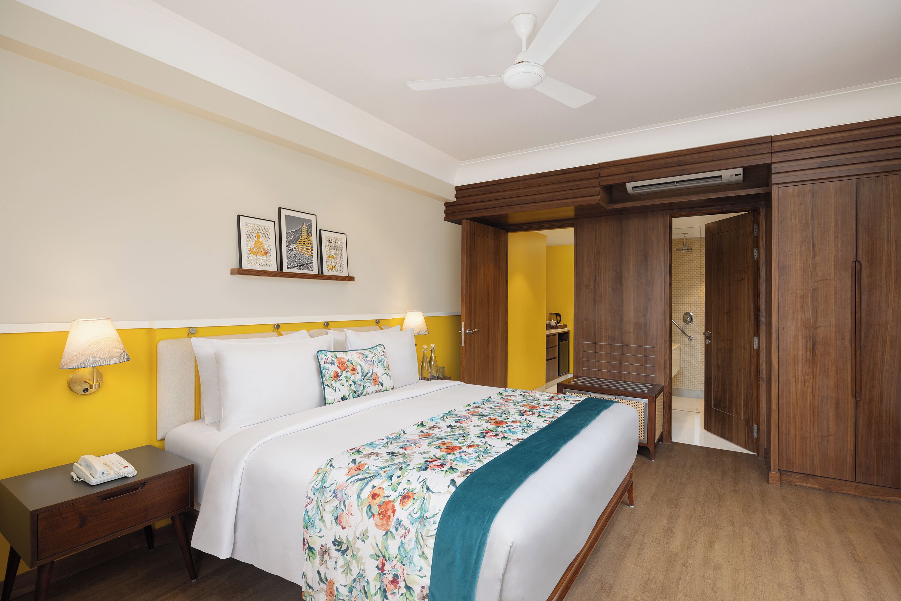 A hotel room with a bed, bedside table, lamp, and a ceiling fan.