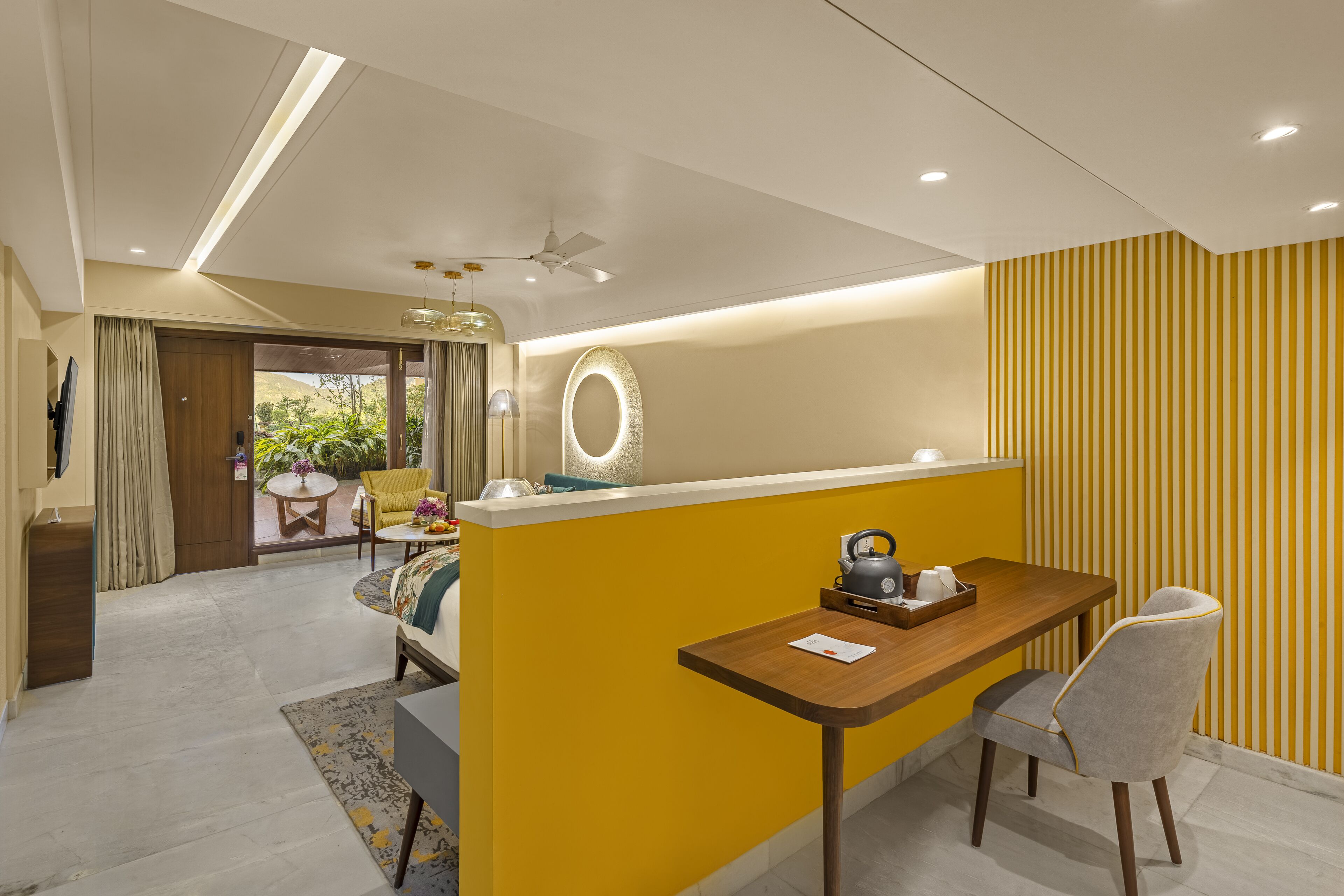A modern kitchen with a yellow accent wall, a wooden table, and a grey chair.