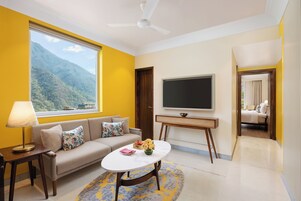 A modern living room with a sofa, a coffee table, a TV, and a view of a mountain.