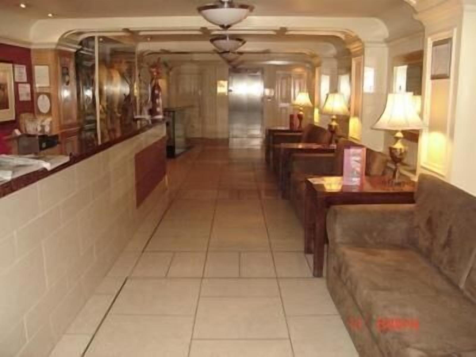 Vestíbulo de hotel con mostrador de recepción, zona de estar y un largo pasillo.