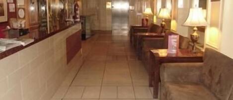 A hotel lobby with a reception desk, seating area, and a long corridor.