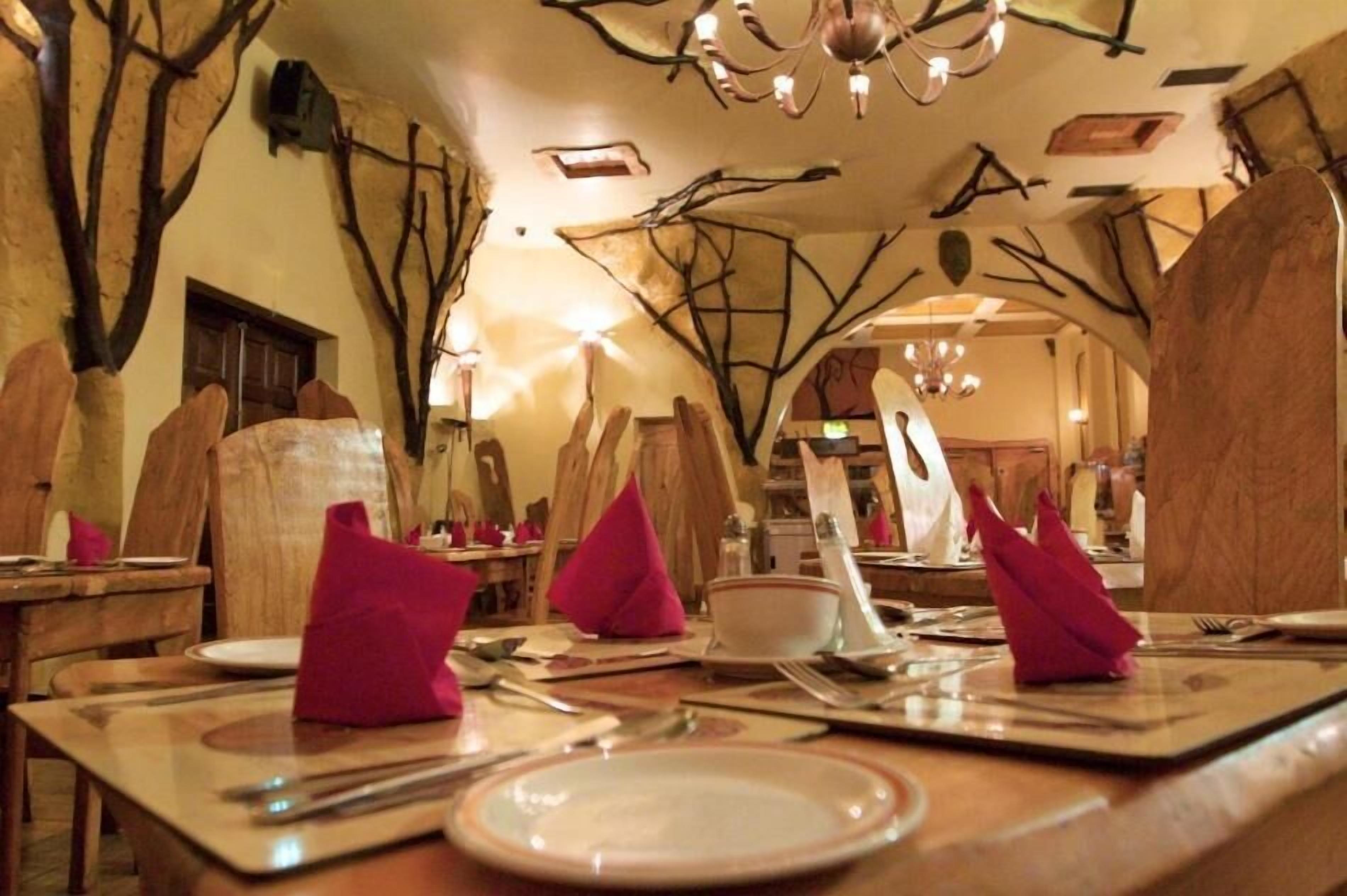 A dining area with wooden tables, chairs, and pink napkins.