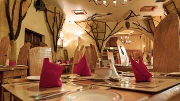 A dining area with wooden tables, chairs, and pink napkins.
